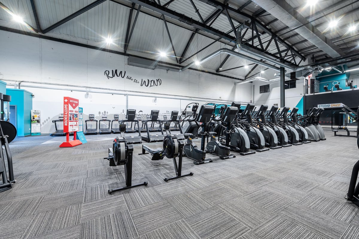 PureGym York: Rows of stationary exercise bikes with screens, arranged in a spacious gym interior.