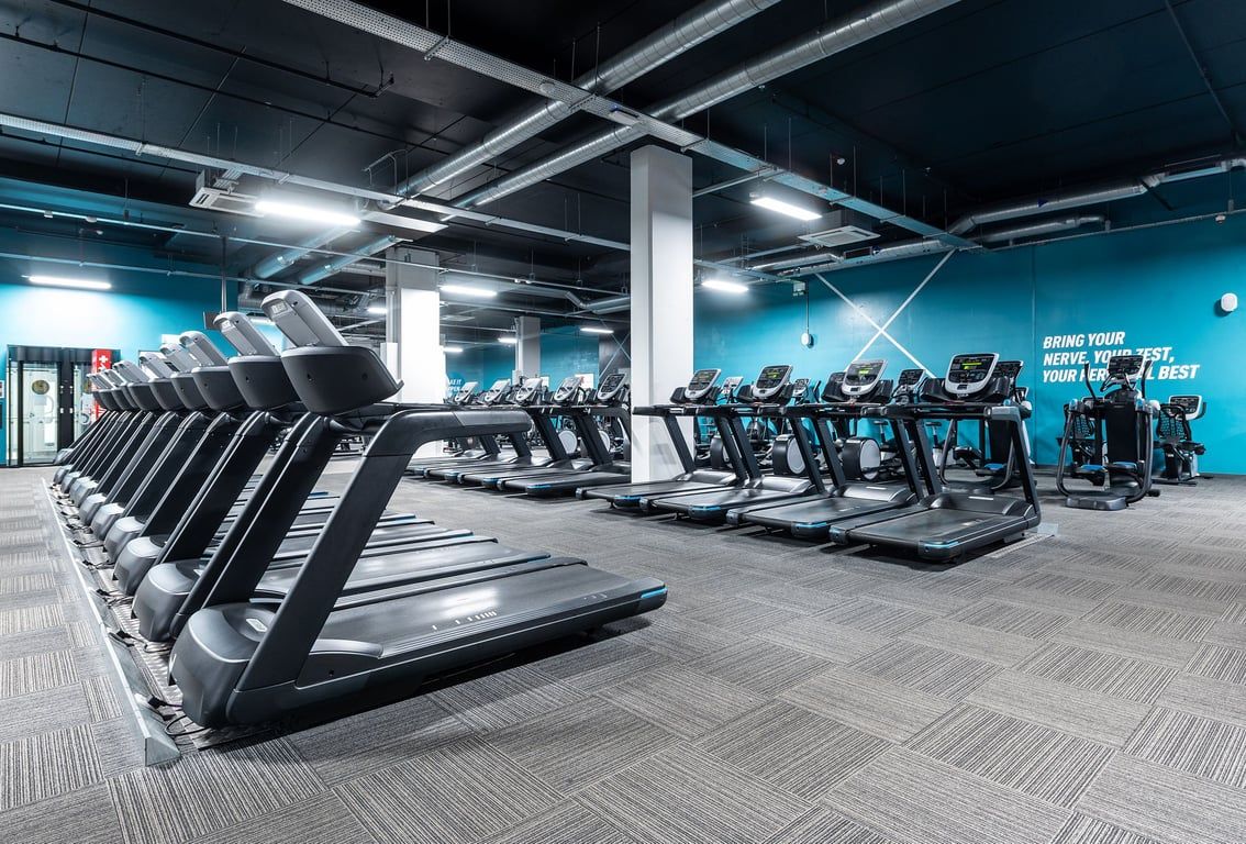 PureGym Norwich Castle Mall: Rows of treadmills and ellipticals in a modern gym with blue accent lighting.