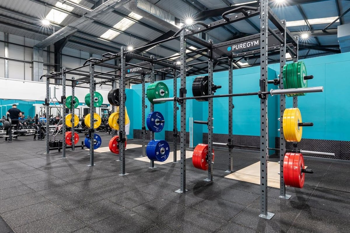 PureGym Leeds Hunslet: Squat racks, weight plates in various colours, rubberized flooring inside a weightlifting area.