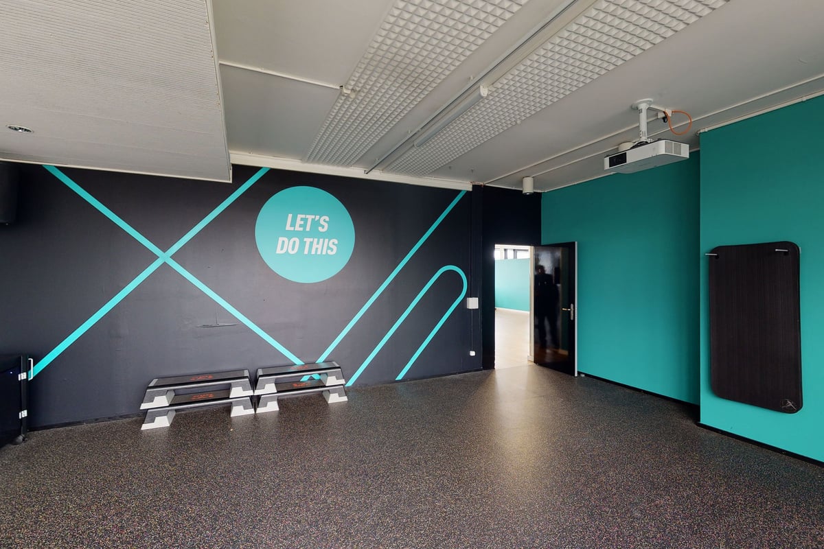 PureGym Dietikon: Studio with benches, neon signage "Let's do this", and teal accent walls.