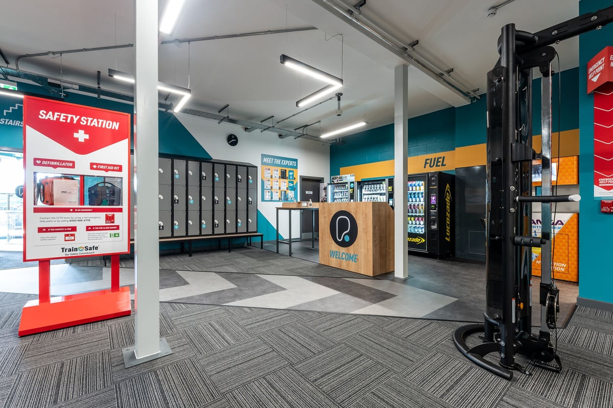 PureGym Shrewsbury Meole Brace: Welcome podio, energy and drink vending machines, lockers, and safety station.
