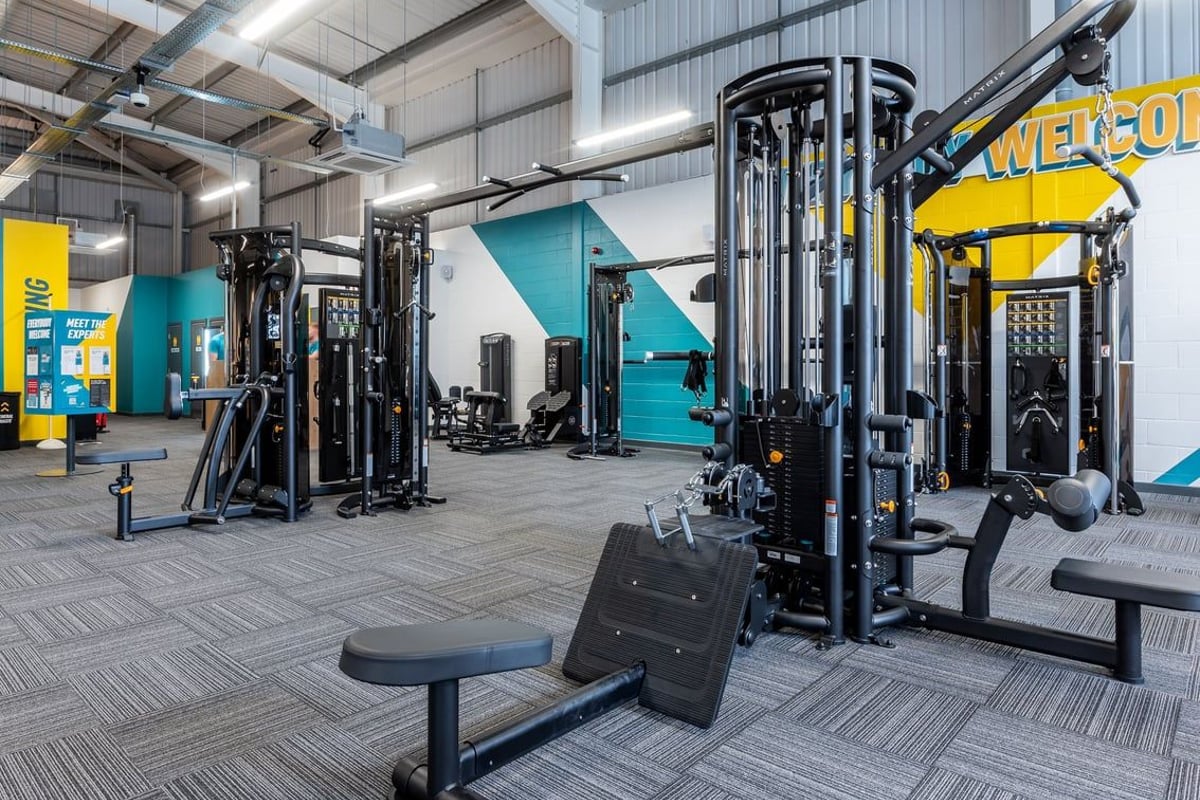 PureGym Spalding: Strength training racks, benches, weights, and mirrors in an industrial-style gym space.