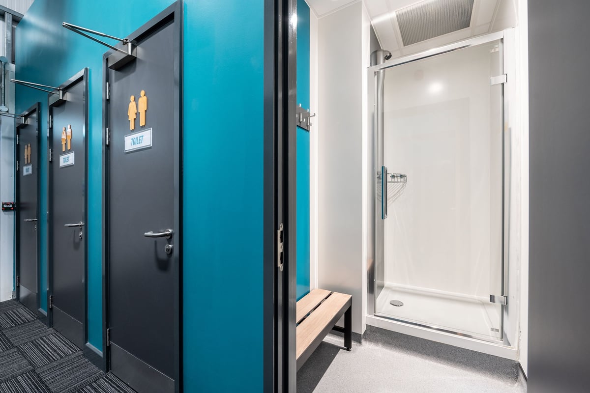 PureGym Alton: Changing room stalls in teal and grey with private shower cubicles.