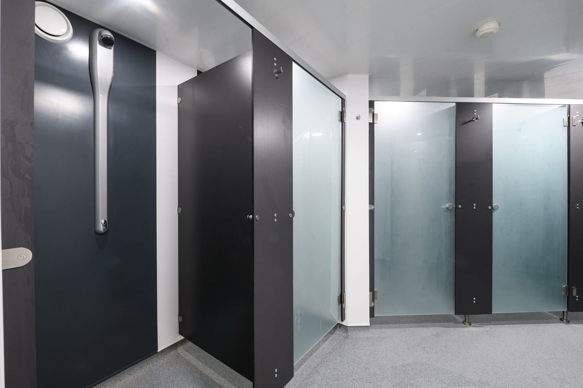 PureGym London Wandsworth: Rows of stalls with privacy doors, typical of changing rooms or shower facilities.