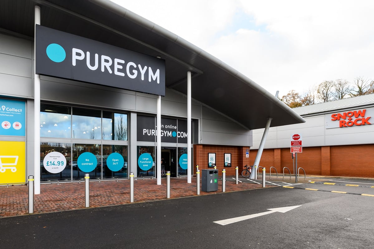 PureGym Exeter Bishops Court: Exterior of a gym building with signage, parking spaces, and entrance doors.