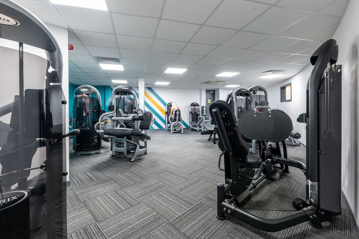 PureGym Bangor Northern Ireland: Resistance machines, free weights, weight benches, and rubberized flooring in a gym setting.