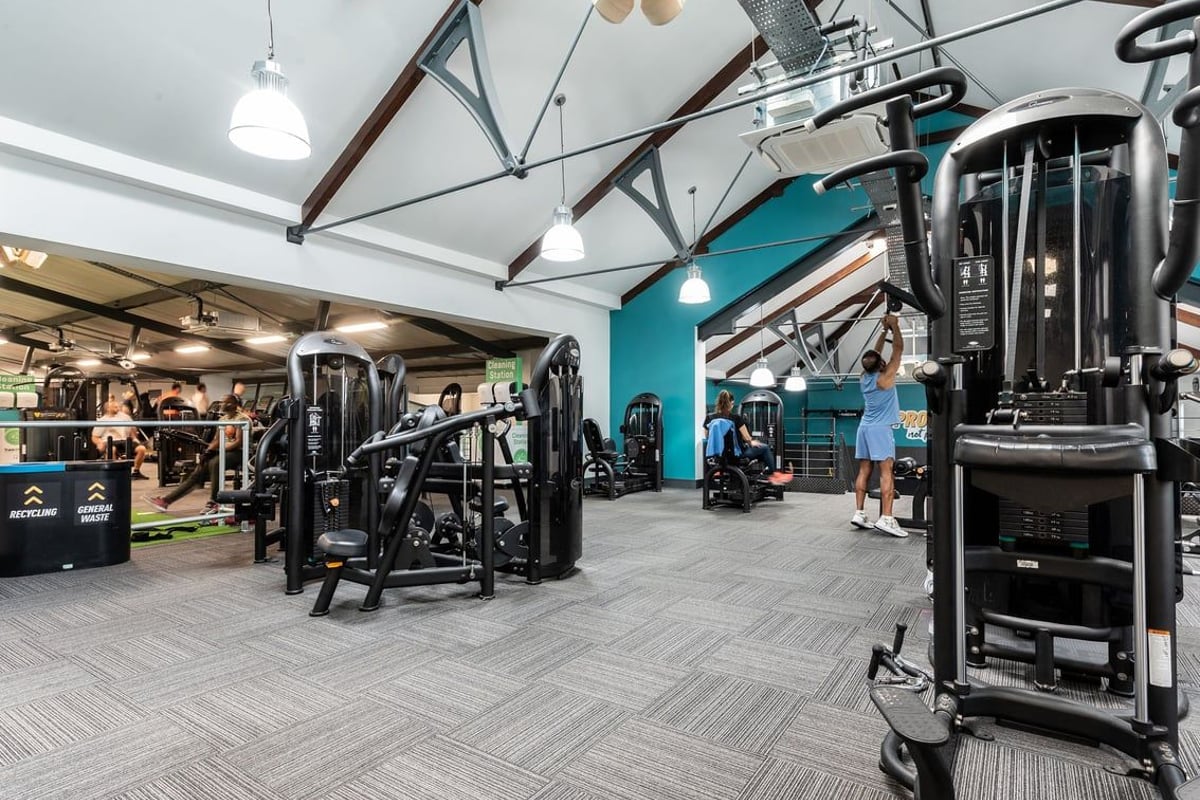 PureGym London Bayswater: Strength training area with weight racks, cable machines, benches, and rubberized flooring.