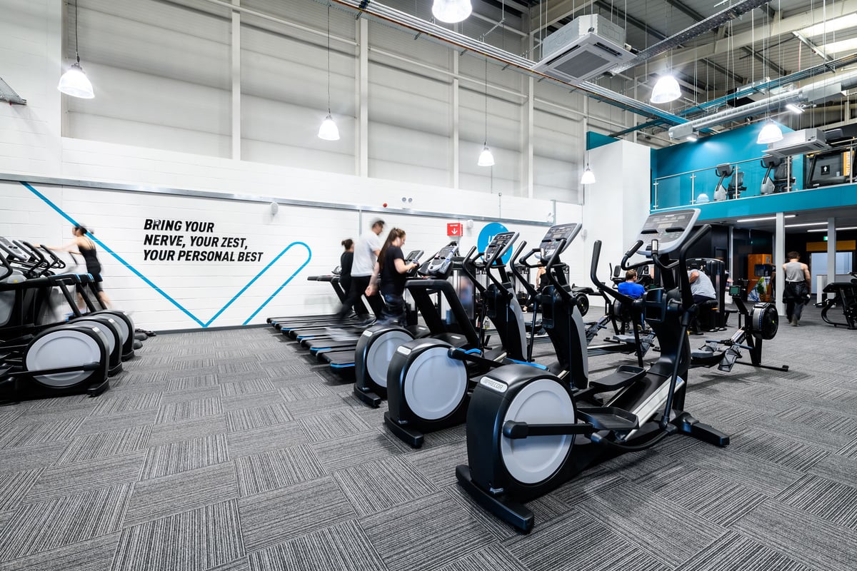 PureGym Folkestone: Rows of upright exercise bikes alongside motivational signage on the wall.