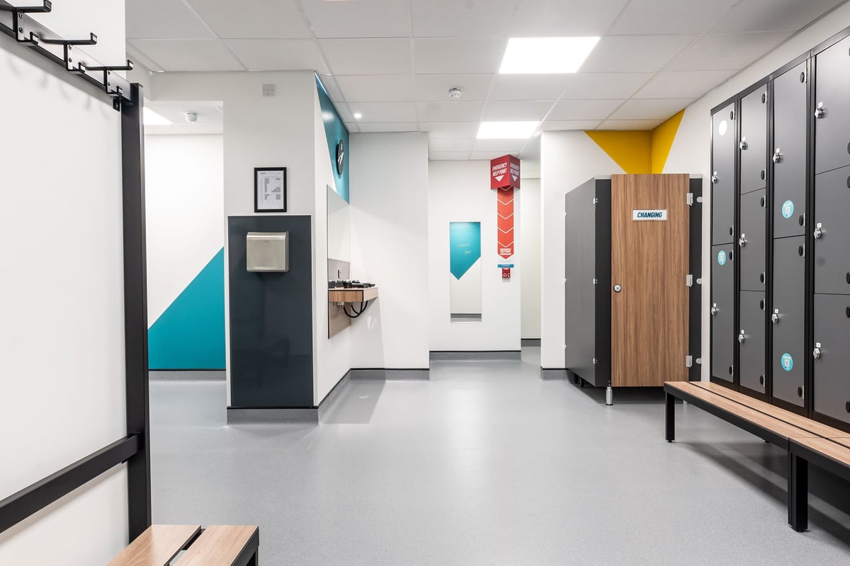 PureGym Sittingbourne: Lockers, benches, and bright geometric wall designs in a fitness changing area.