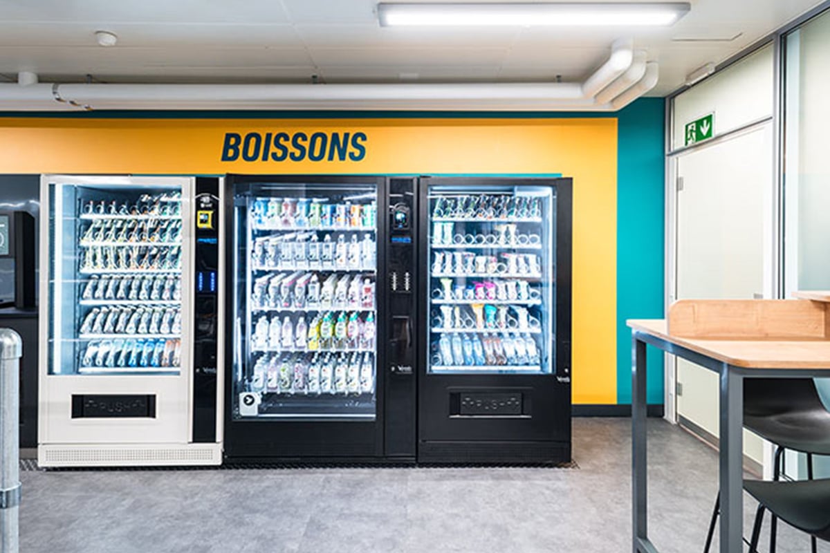 PureGym Fribourg: Des distributeurs automatiques ainsi que des tables et des chaises.