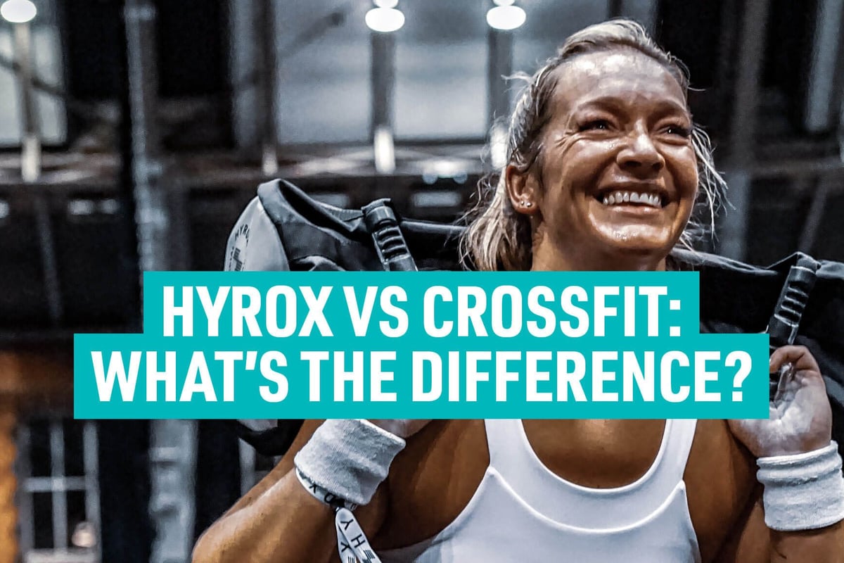 Smiling woman lifting heavy bag on shoulders in gym with bright lights above