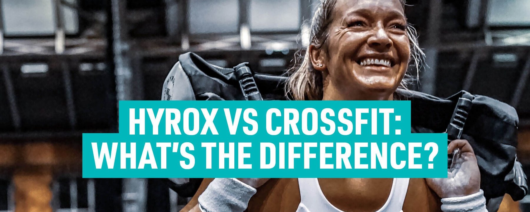 Smiling woman lifting heavy bag on shoulders in gym with bright lights above