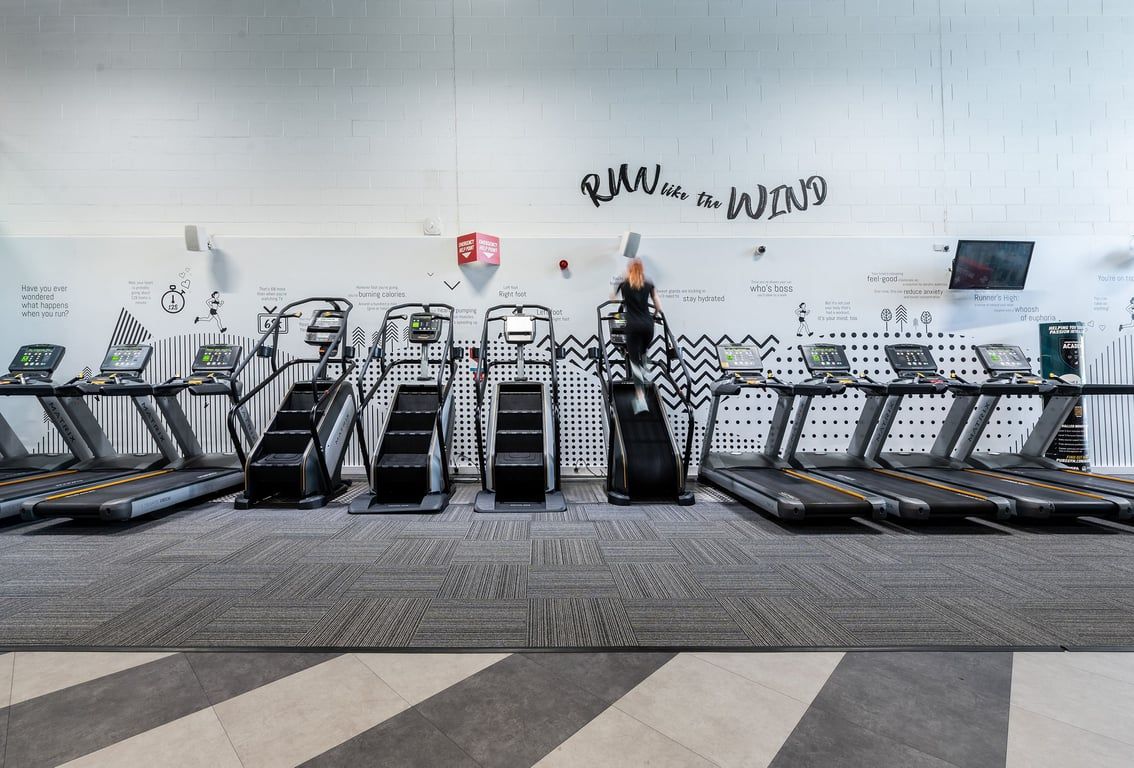 PureGym Southampton Central: Rows of treadmills and customised graffiti art on the wall inside a modern gym facility.