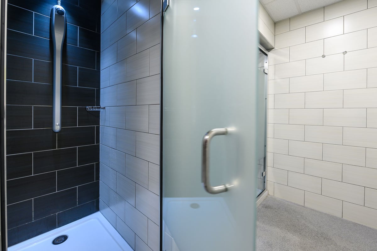 PureGym London Acton: Tiled shower area with disability grab rails and non-slip flooring.