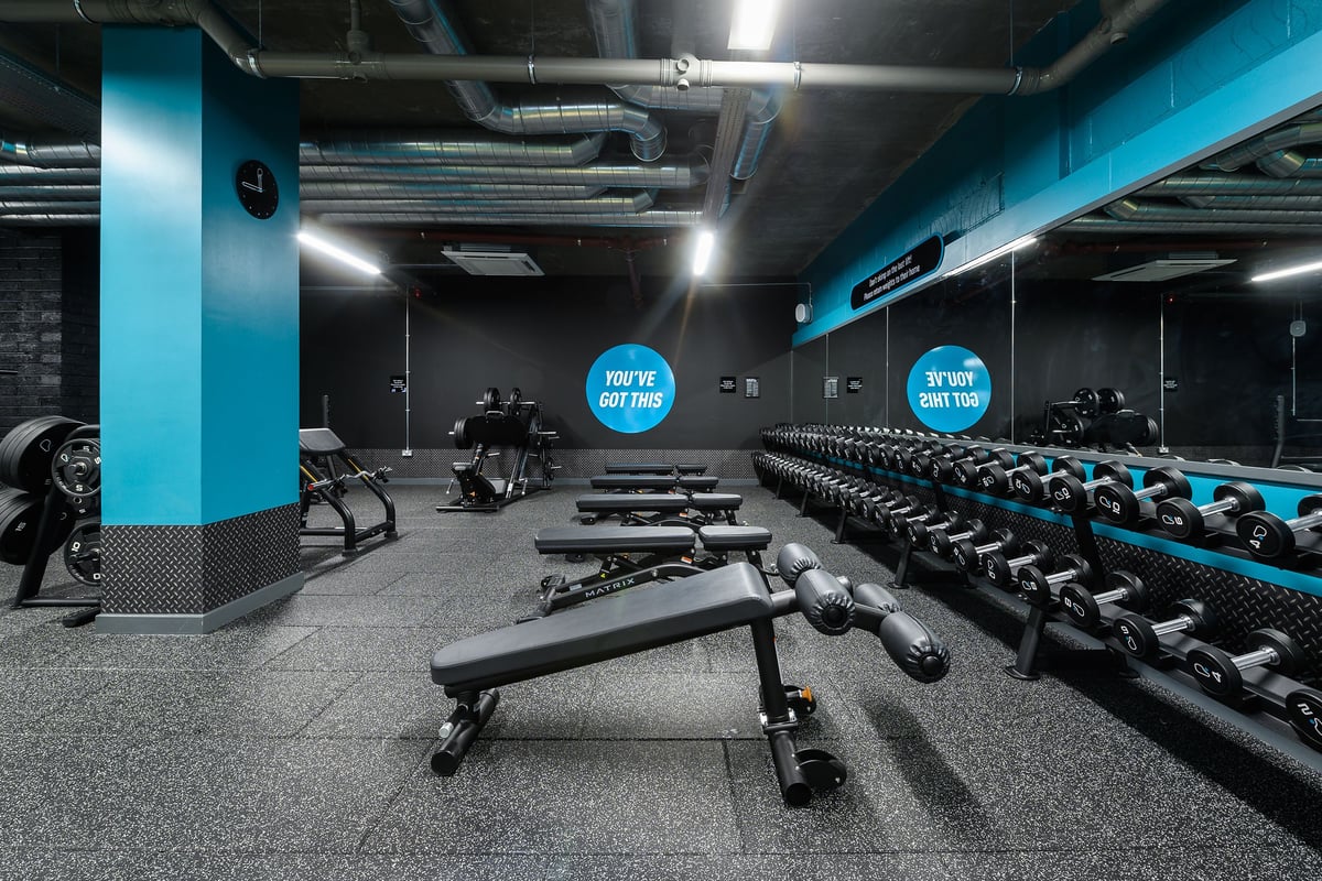 PureGym London Camberwell Southampton Way: Rows of weights benches, dumbbells, and weight racks in blue-accented gym space.