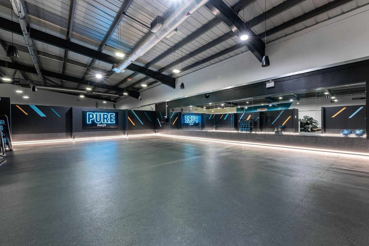 PureGym Lincoln St Marks Centre: Large open gym floor with pure branding, dimmed lighting, and rubberized flooring.