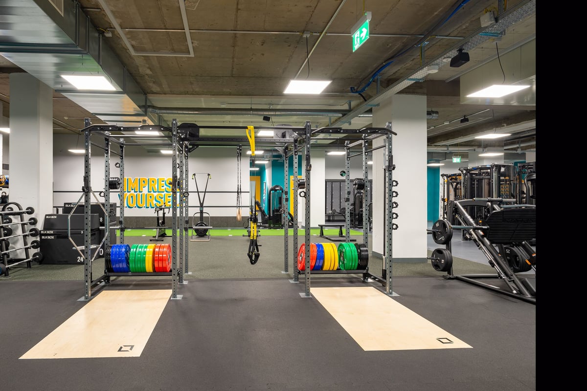 PureGym La Chaux-de-fonds: Weightlifting racks, plates in multiple colours, rubberized flooring, and mirrored walls.
