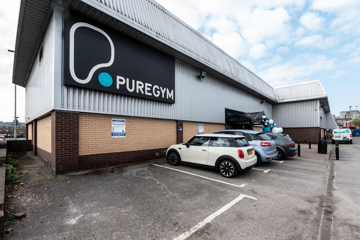 PureGym Warrington Central: Exterior of a gym facility with its logo and parking spaces.