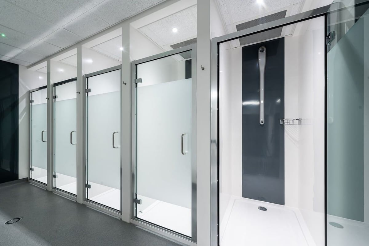 PureGym Ashford Warren Retail Park: Rows of frosted glass shower stalls or changing cubicles with doors.