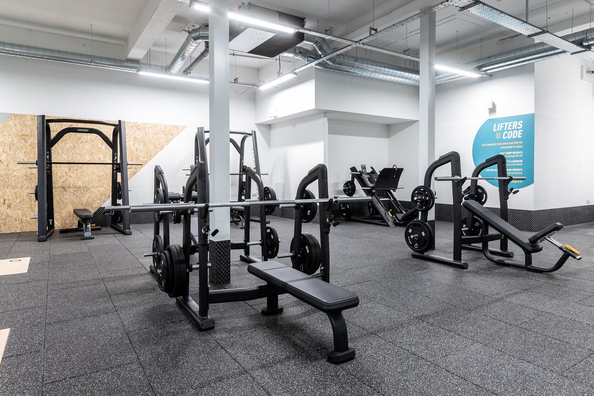 PureGym Edinburgh Craigleith Retail Park: Rows of plate-loaded weight machines, benches, and rubberized flooring in a gym.