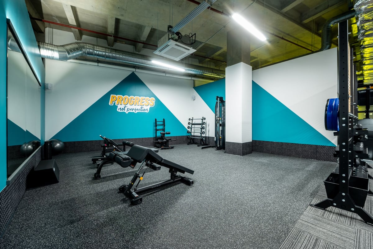 PureGym Uxbridge: Rows of workout benches, free weights, and resistance machines on rubberized floor.