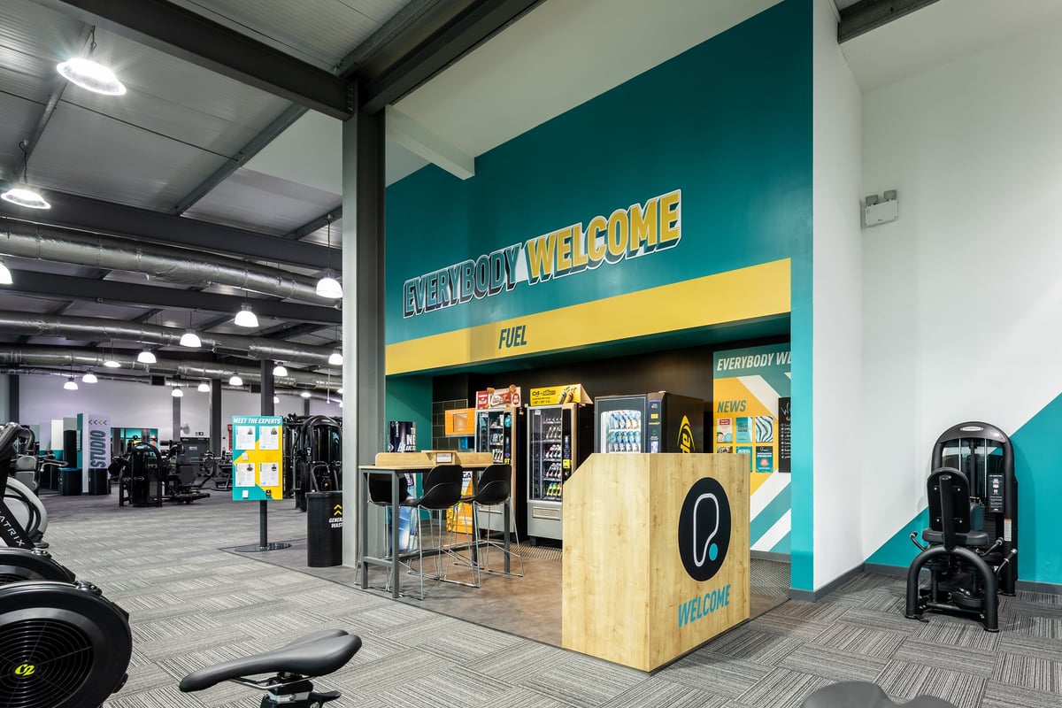 PureGym Cardiff Gate: Weights, benches, resistance machines on rubberized flooring in a gym reception area.