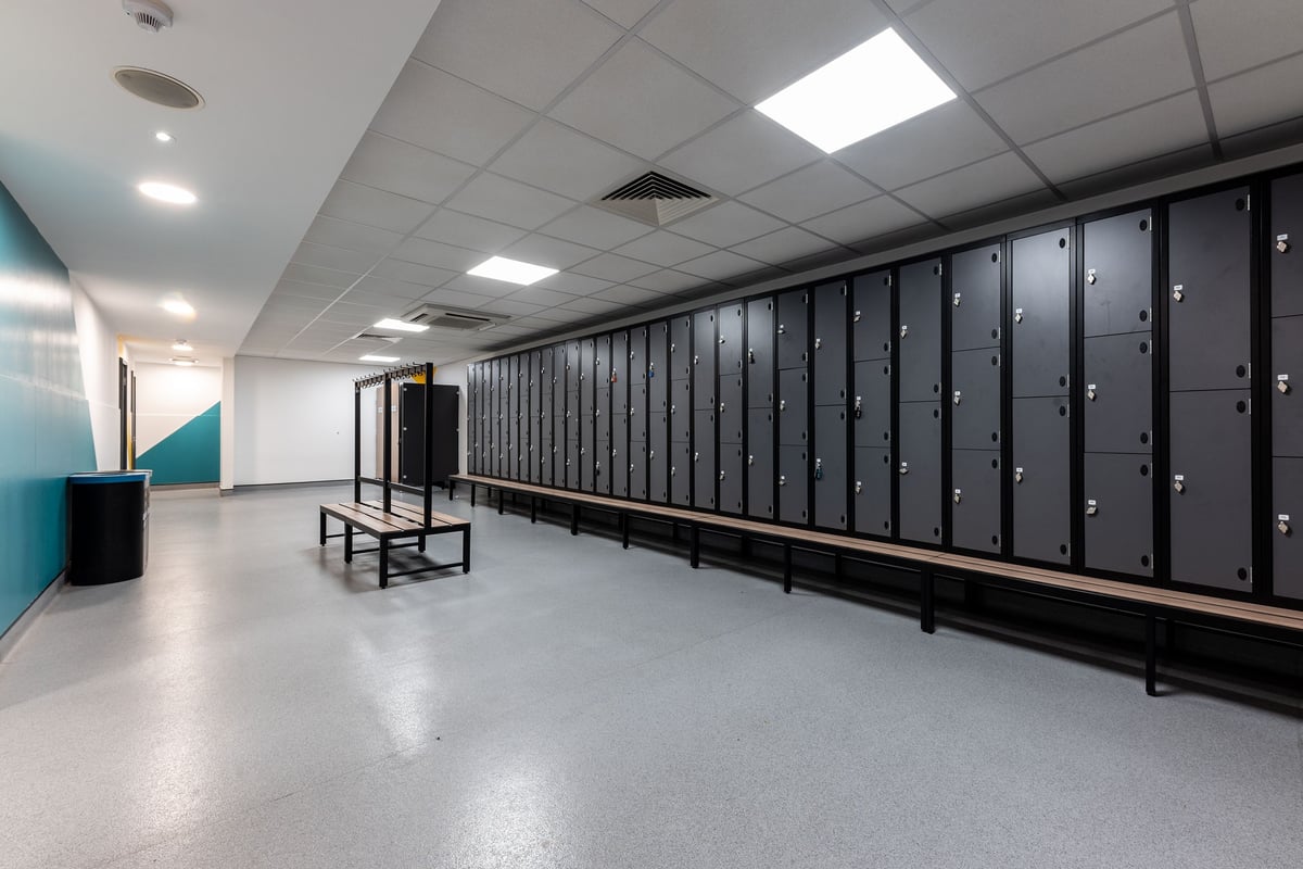 PureGym London Putney: Rows of lockers, benches in an interior space with tiled flooring.