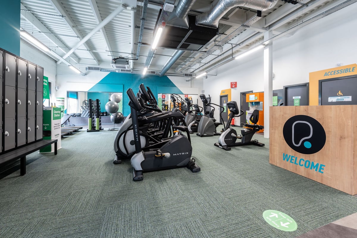 PureGym Aldershot Westgate Retail Park: Rows of stationary bikes, ellipticals, racks of dumbbells in a bright gym interior.