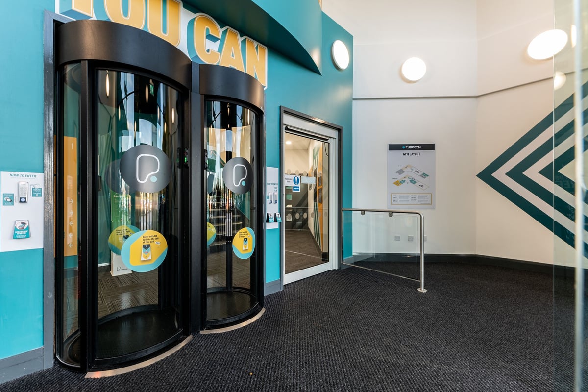 PureGym Livingston: Entrance area with self-service kiosks, turquoise branding, and directional signage.