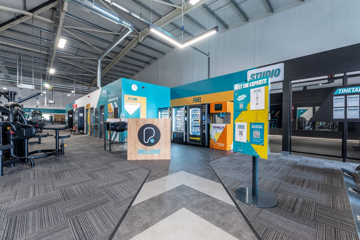PureGym Durham City Retail Park: Gym studio with colourful kiosks, open floor space, and branded wall graphics.