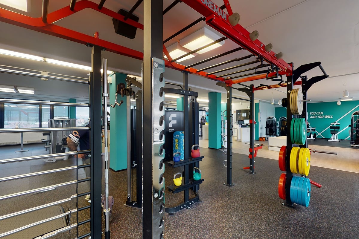 PureGym Dietikon: Red squat racks, weight plates, resistance machines, and rubberized flooring.