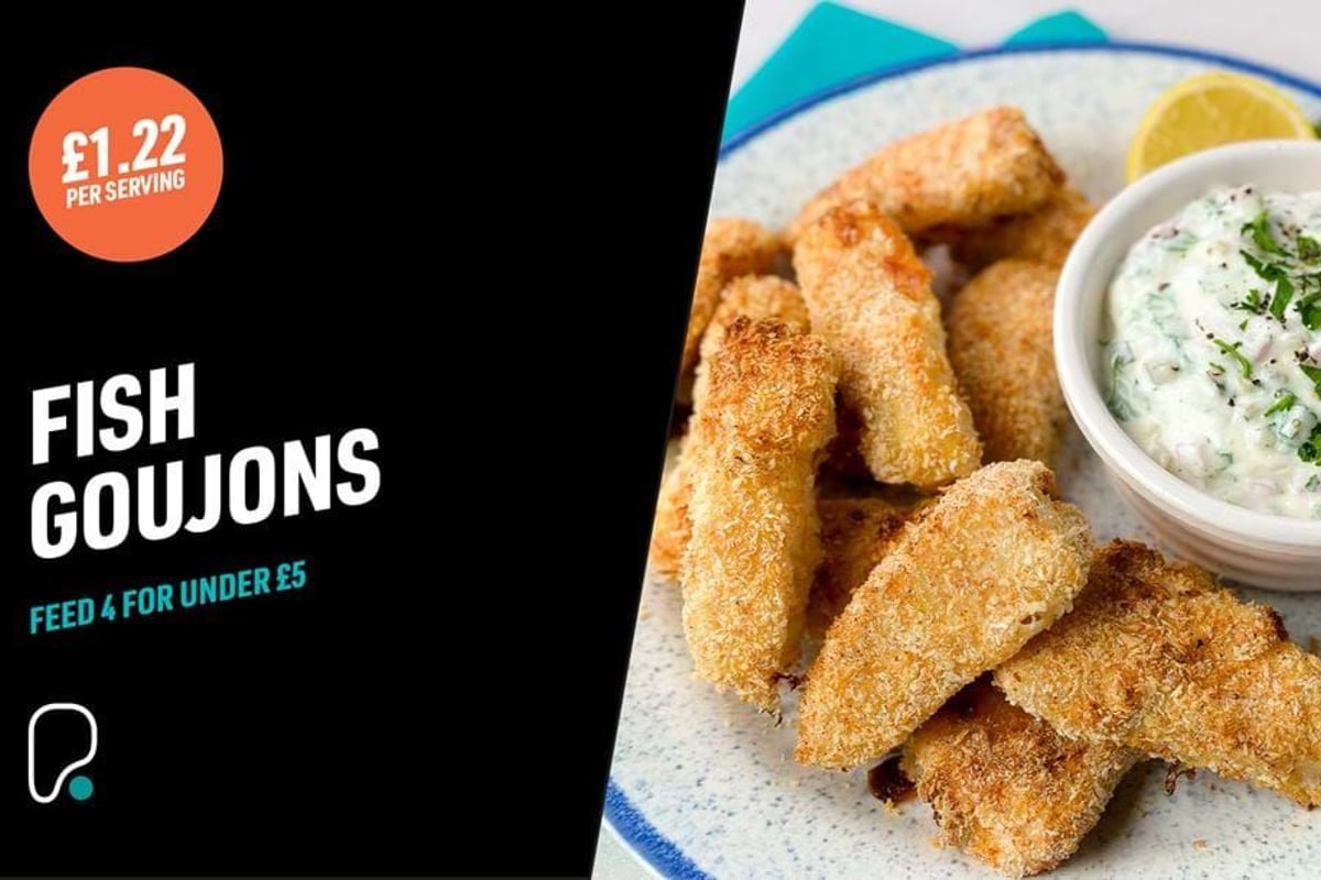Breaded fish goujons on a plate with a bowl of creamy herb dip and lemon wedge