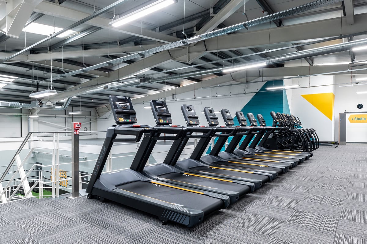 PureGym Sheffield Crystal Peaks: Rows of treadmills in a gym with industrial ceiling and ductwork visible.
