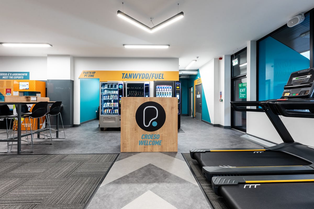 PureGym Bangor Wales: Treadmills, vending machines, seating area, and a rubberized gym floor.