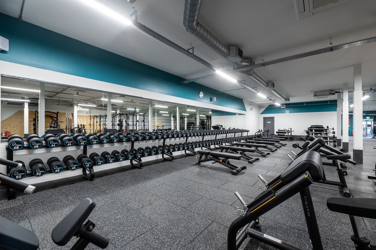 PureGym Derby Kingsway Retail Park: Rows of dumbbell racks, free weights, benches, and rubberized flooring inside a gym.