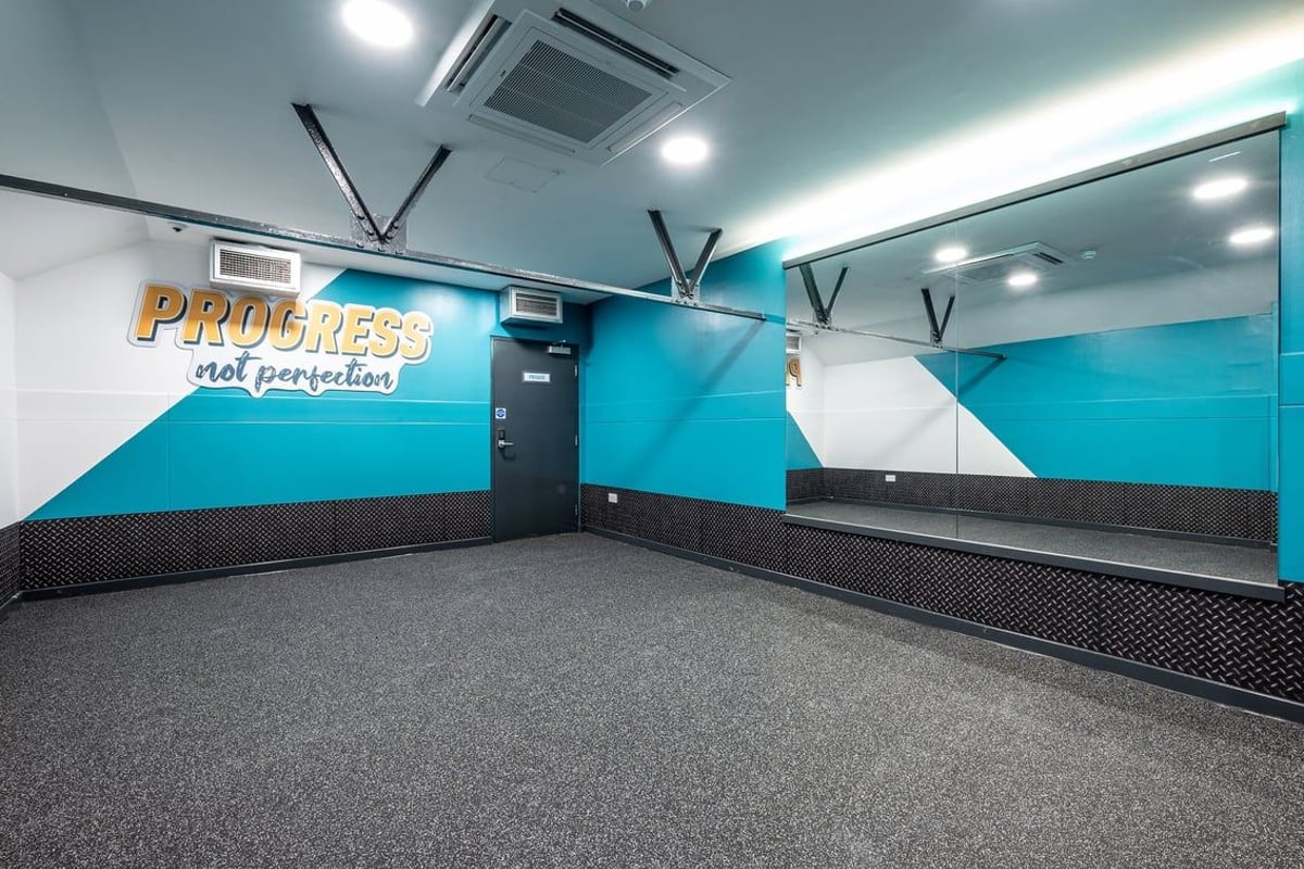 PureGym London Marylebone: Teal and white room with motivational signage, air conditioning units, and rubberized flooring.
