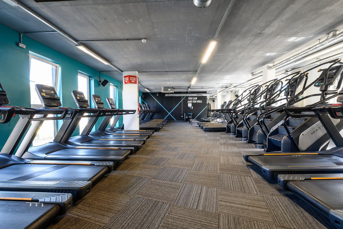 PureGym London Greenwich: Rows of treadmills, stationary bikes, and weight machines inside a fitness studio.