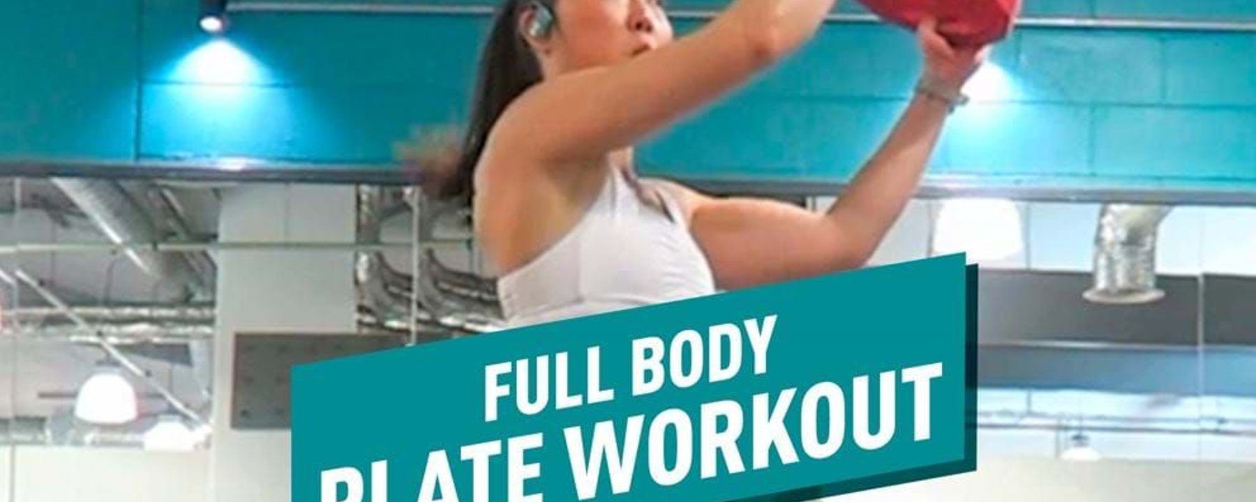 Woman in gym lifting red weight plate during workout session