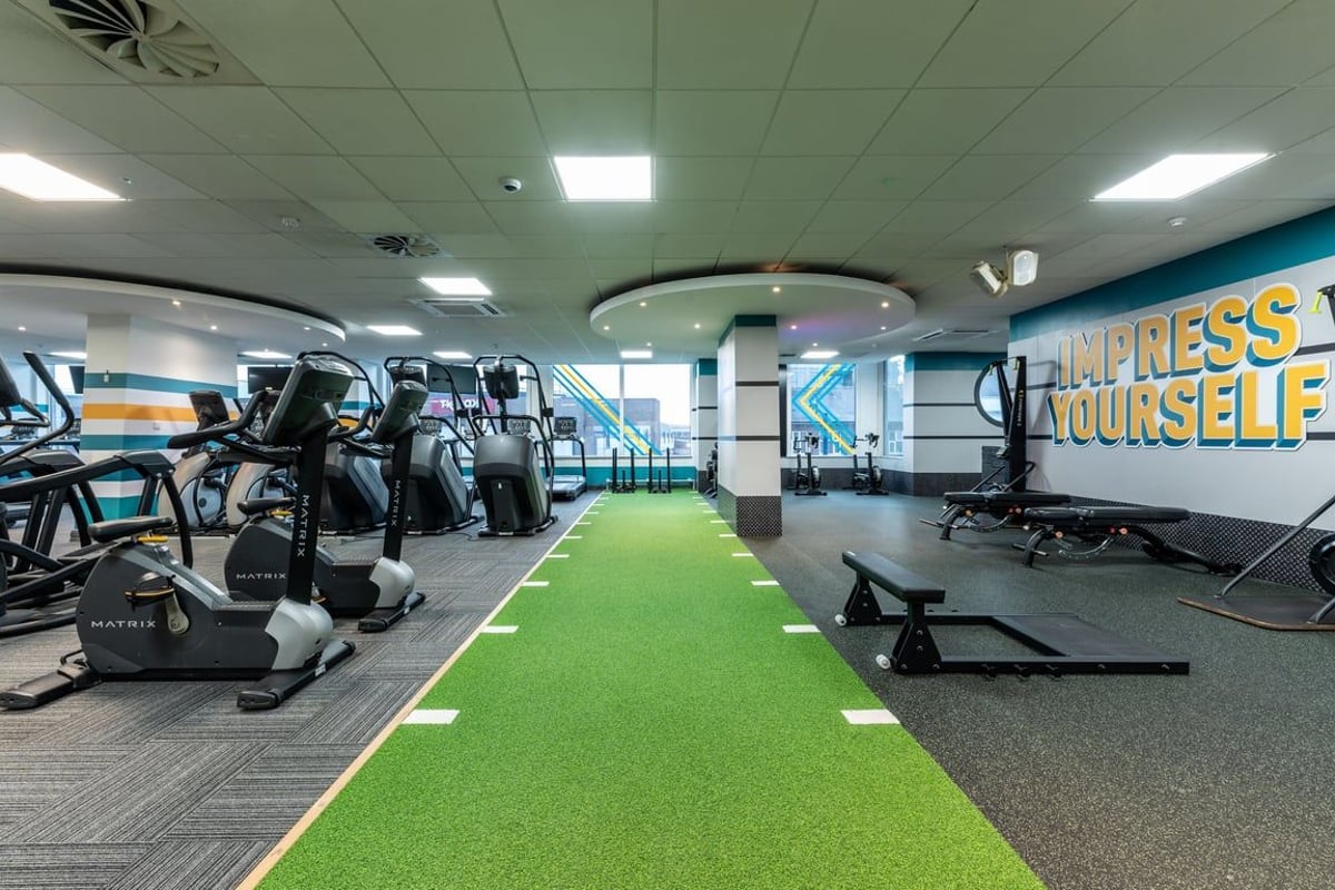 PureGym London Edgware: Rows of exercise bikes, treadmills, weight benches, and turf on the gym floor.