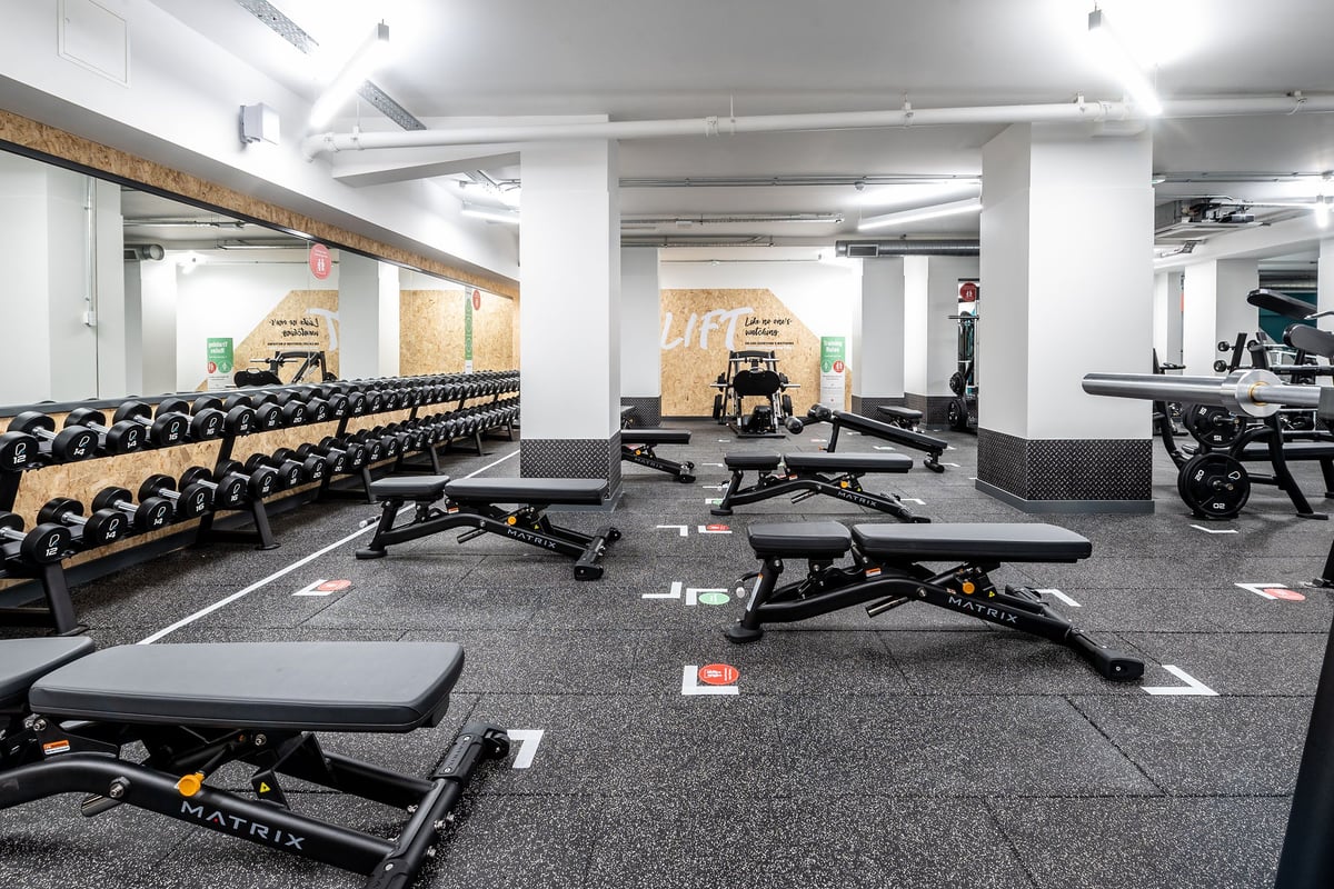 PureGym London Twickenham: Weight benches, squat racks, dumbbell racks, and rubberized flooring in a weightlifting area.