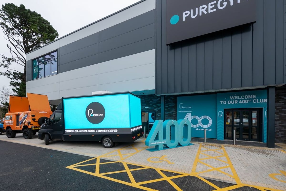 PureGym Plymouth Derriford: Industrial building entrance with PureGym logo, trucks, exterior signage.