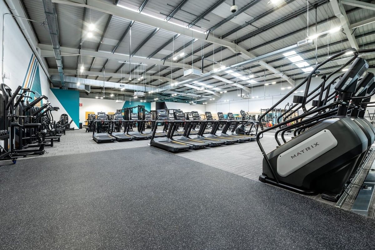 PureGym Newbury: Rows of treadmills, ellipticals, and other cardio machines in a large gym space with high ceilings.