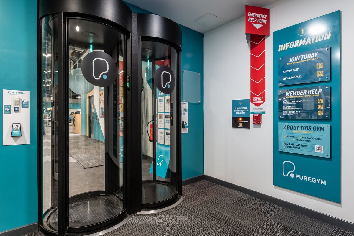 PureGym Southampton Bitterne: Revolving doors, information posters advertising gym memberships, teal colour scheme.