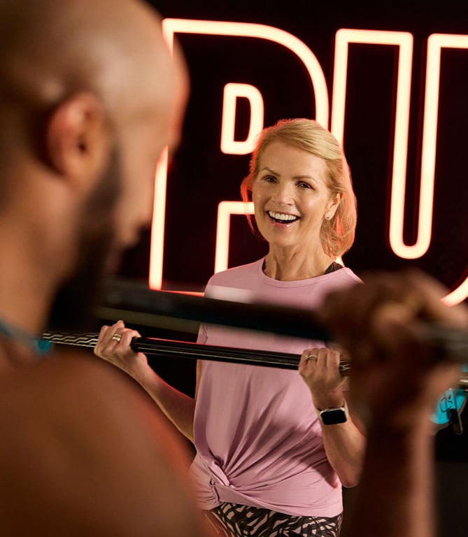 Feel PureGym Good: Female PureGym member smiling at male lifting weights