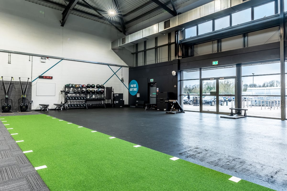 PureGym Leeds Hunslet: Gym space with resistance machines, green turf area, free weights, and floor markings.