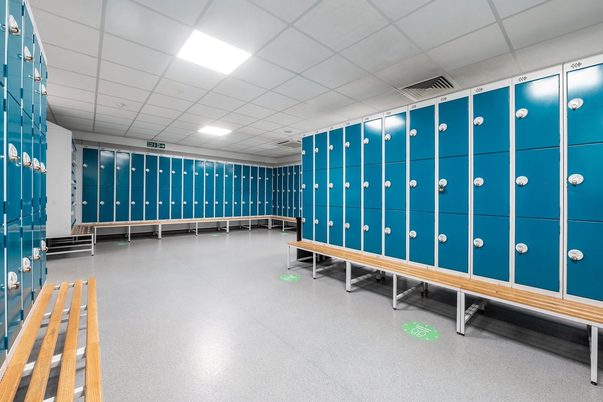 PureGym Warrington Central: Blue lockers, wooden benches, tiled floors - locker room.