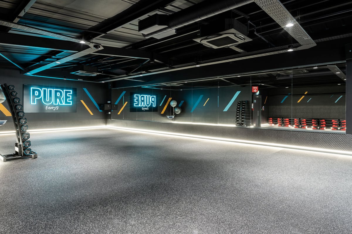 PureGym Northallerton: Rows of bright neon-lit equipment areas, treadmills, free weights, and mirrored walls.