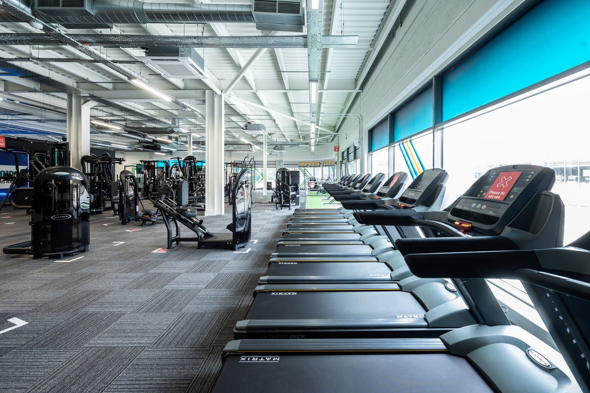 PureGym Aldershot Westgate Retail Park: Rows of treadmills and weight machines in a brightly lit modern gym interior.