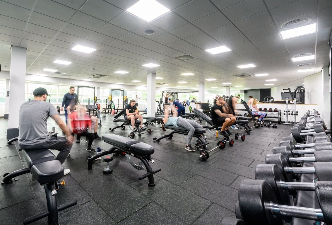 PureGym Newcastle Longbenton: Rows of treadmills, weight benches, dumbbells, and cardio machines in a well-lit gym interior.