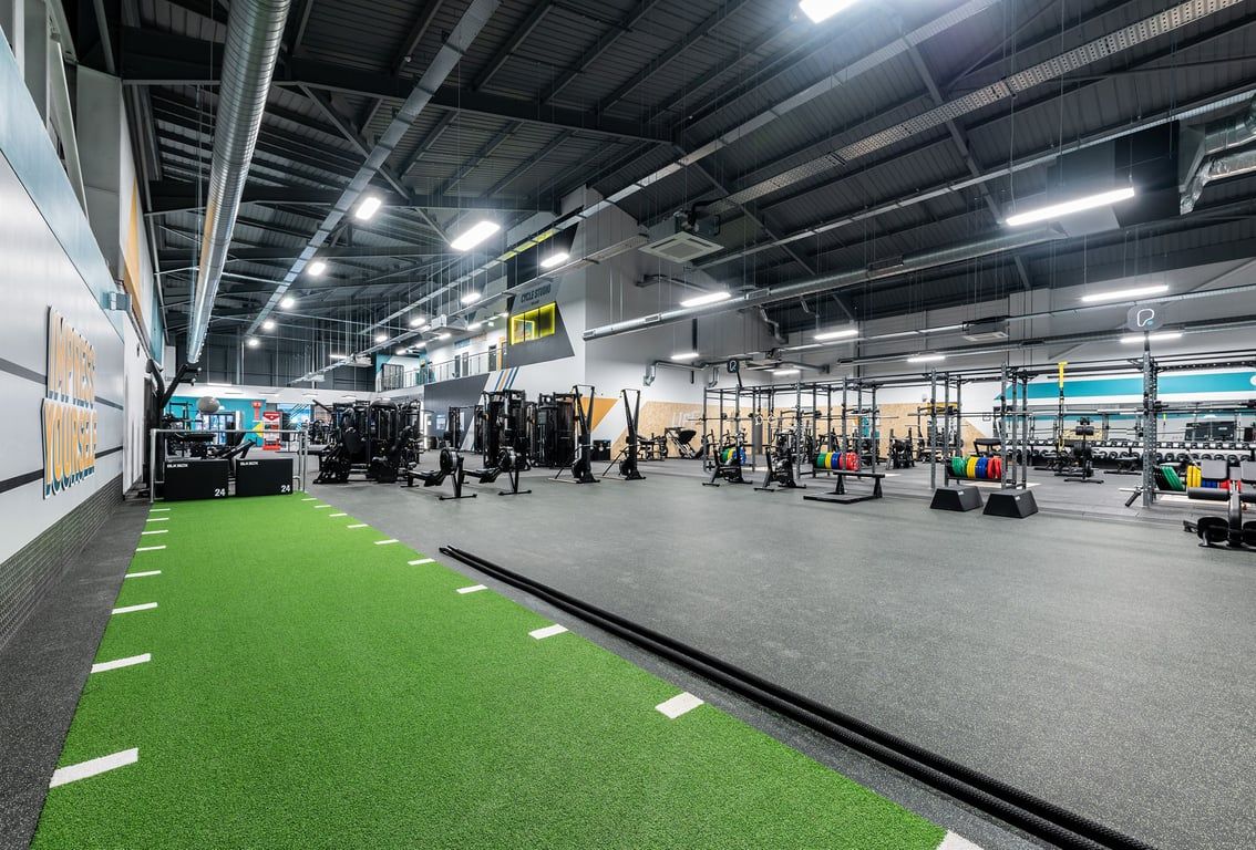PureGym Sheffield Meadowhall Retail Park: Racks of weights, benches, turf area, and ceiling-mounted lighting in a gym space.
